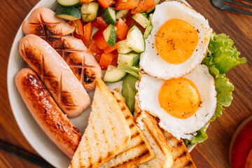 A hearty breakfast of fried eggs, sausages and toast.