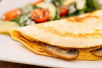 Tortilla with champignons with salad on table.