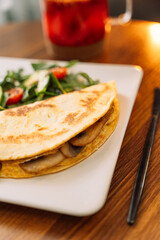 Tortilla with champignons with salad in a square white plate.