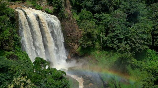 Majestic Curug Sewu waterfall with vibrant rainbow in lush tropical forest. Powerful cascading water creates a dramatic natural scene. Concept of beauty, nature, and wonder