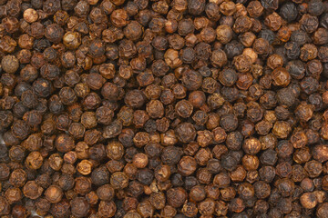 A close-up, full-frame shot of dried black peppercorns, showcasing their texture and color