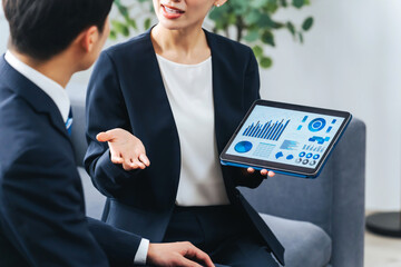 ロビーでタブレットを見ながら商談する男女ビジネスパーソンのグループ