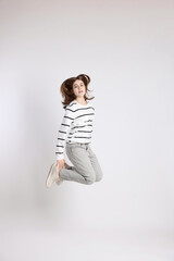 Beautiful teenage girl jumping on light background