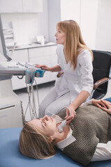 female doctor performs ultrasound of thyroid gland on woman patient in clinic using modern device....