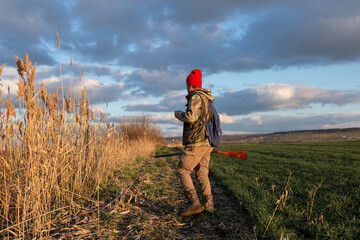 Mature hunter man holding a shotgun and walking through a field