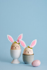 Cute Easter eggs bunny in egg holders on blue background. Vertical postcard. Place for your text