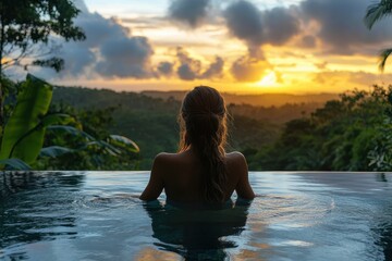 Fototapeta premium Woman Relaxing in Infinity Pool Overlooking Lush Jungle at Sunset with Dramatic Sky and Clouds