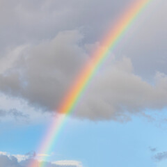amazing bright rainbow in beautiful evening blue cloudy sky after rain and thunder with flash sun light streaming thruogh the clouds, weather thunderstorm concept
