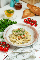 Pasta with chicken and mushrooms in creamy sauce, restaurant. Vertical frame.