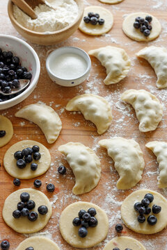 Homemade sweet pierogi, dumplings  filled with fresh blueberries during the preparation process, close up view. Traditional polish food.