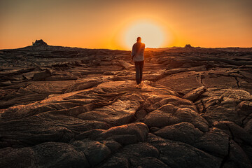 Man walking at sunset on solidified lava in Erta Ale volcano in Afar region, Ethiopia