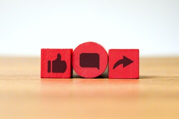 Three wooden cubes with like, comment and share icon. Social media concept.