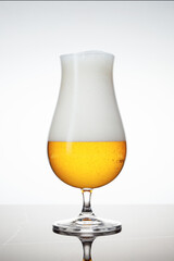 Glass of light beer on a white granite background.
