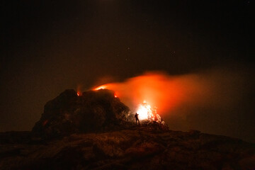 Man inspecting a hornito from up close at night in Erta Ale volcano in Afar region, Ethiopia