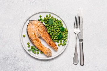 Roasted salmon steak with fresh green peas and mint on white plate. Healthy food light background with copy space