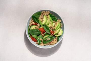 Quinoa spinach avocado salad on light background top view. Healthy food concept