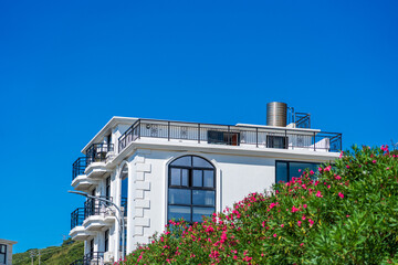 Elegant Coastal Building Surrounded by Vibrant Flora Against a Clear Blue Sky