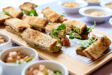 sandwiches with salmon, cheese and lettuce on a wooden board