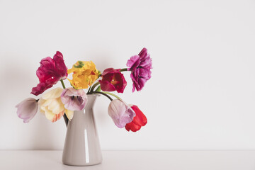 Beautiful bunch of multicolored terry tulip flowers in full bloom in vase against white background. Minimalist spring still life. Copy space for text.