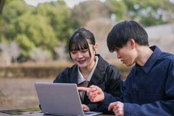 ノートパソコンで作業する大学生のカップル