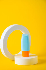 Cosmetic product in tube, bottle, lotion or serum with stylish props on yellow background. 
