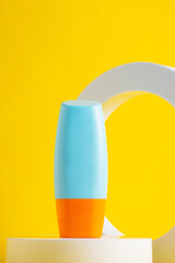 Cosmetic product in tube, bottle, lotion or serum with stylish props on yellow background. 