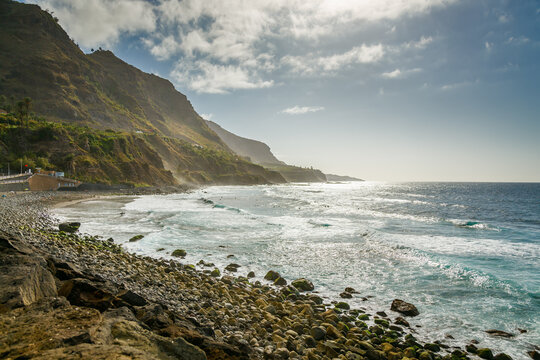 A stunning view of Playa del Socorro, Tenerife, showcasing its volcanic black sand, crashing waves, and vibrant cliffs, attracting both surfers and nature seekers