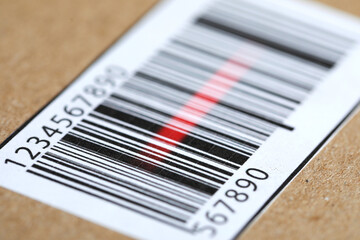 Parcel with label, closeup. Red laser light on barcode for scanning