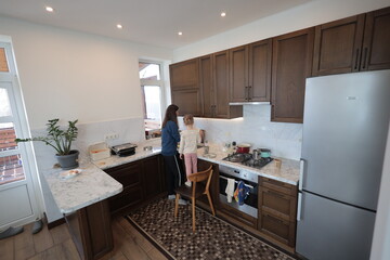 Mother and a child girl cooking and eating indoors together 