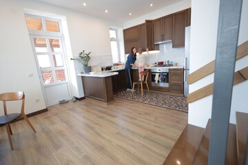 Mother and a child girl cooking and eating indoors together 