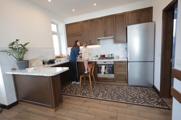 Mother and a child girl cooking and eating indoors together 