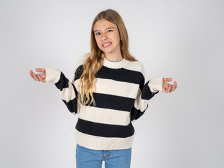 Clueless beautiful caucasian teen girl wearing striped sweater shrugs shoulders with hesitation,...