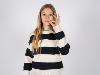 beautiful caucasian teen girl wearing striped sweater mouth and lips shut as zip with fingers. Secret and silent, taboo talking. © Jihan