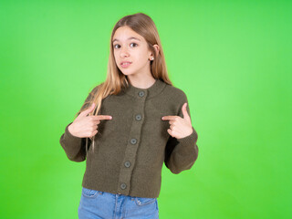 Embarrassed beautiful caucasian girl wearing green sweater indicates at herself with puzzled...