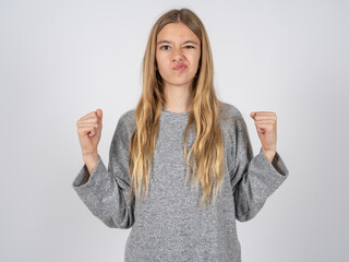 Irritated beautiful caucasian girl wearing grey track-suit blows cheeks with anger and raises...