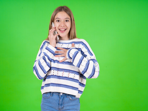 Smiling beautiful caucasian girl wearing striped sweater talks via cellphone, enjoys pleasant great conversation. People, technology, communication concept