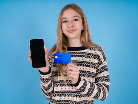 Photo of adorable beautiful caucasian girl wearing striped sweater  holding credit card and Smartphone. Reserved for online purchases