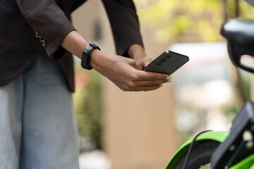 Digital Engagement and Eco-Friendly Lifestyle. A close-up of a woman using her smartphone while leaning against her bicycle.