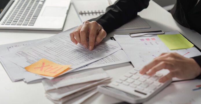 Tax preparation and analysis. Business professional reviewing tax documents and financial statements in the office.