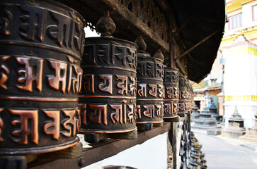 Obraz premium Prayer wheels or mani holy wheel and mantra written tibetan on wall Swayambhunath pagoda or Monkey Temple for nepali people foreign travelers rotate respect praying of lord buddha in Kathmandu, Nepal