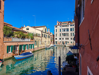 Calm water in a narrow canal in Venice. Sunny day