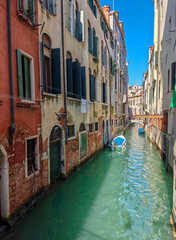 Calm water in a narrow canal in Venice. Sunny day