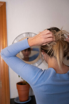 woman touching up her hair in front of a mirror
