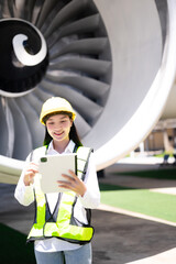 Female aviation engineer in safety gear inspecting an airplane engine, embodying professionalism