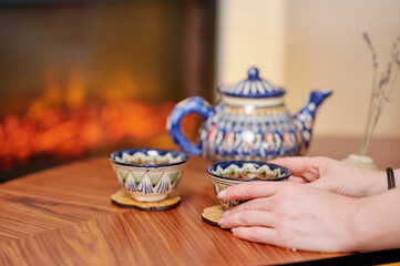 Fototapeta premium Blue ceramic teapot with matching cups placed near warm fireplace, showcasing serenity and refined cultural aesthetics