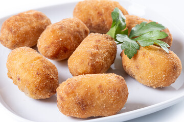 Fried cod croquettes on wooden table. Close up
