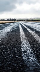 Naklejka premium Wet road with stop sign reflecting rainwater under overcast sky in urban environment
