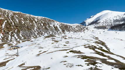 Aerial view of ski lifts. It is a sunny winter morning and there is a lot of snow on the mountain.