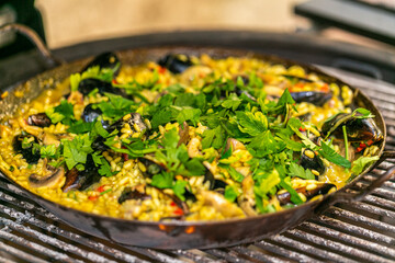 The chef prepares a traditional seafood paella on the grill.Traditional spanish dish. Fresh and Colorful Spanish Seafood Paella. Mediterranean cuisine and seafood dishes.