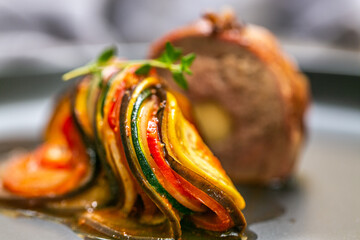 Chef preparing traditional Provençal vegetable dish Ratatouille with stuffed rolled meat on the grill. French food. Healthy eating. Delicious vegetable